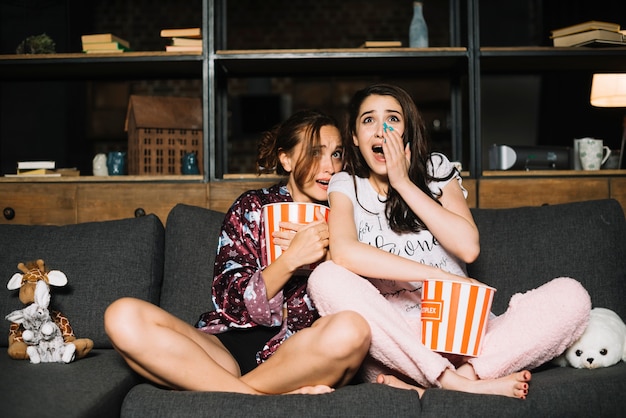 Портрет двух испуганных женщин-друзей, смотрящих телевизор