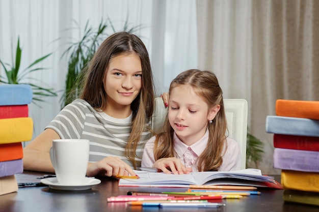 Portrait of two girlfriends studying at the table with a lot of books.