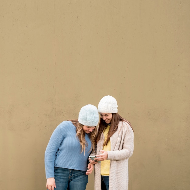 Free photo portrait of two girls in front of a wall