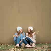 Free photo portrait of two girls in front of a wall