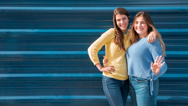 Free photo portrait of two girls in front of a wall