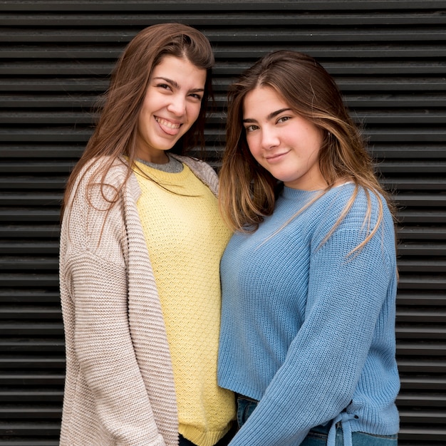 Free photo portrait of two girls in front of a wall