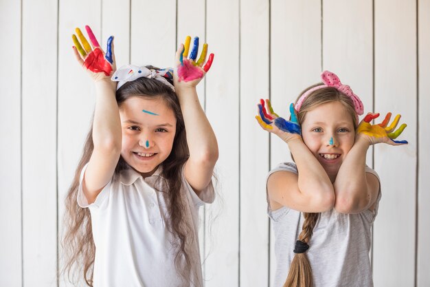カメラを探して塗られた手を示す彼らの手を上げる二人の少女の肖像画