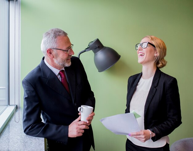 Portrait of two happy mature businessman and young businesswoman taking break