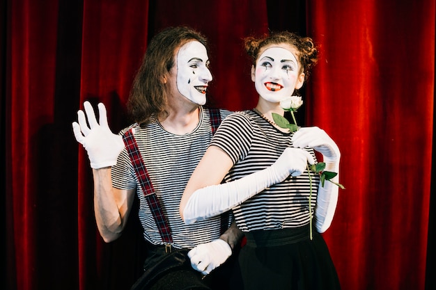 Portrait of two happy mime artist in front of red curtain