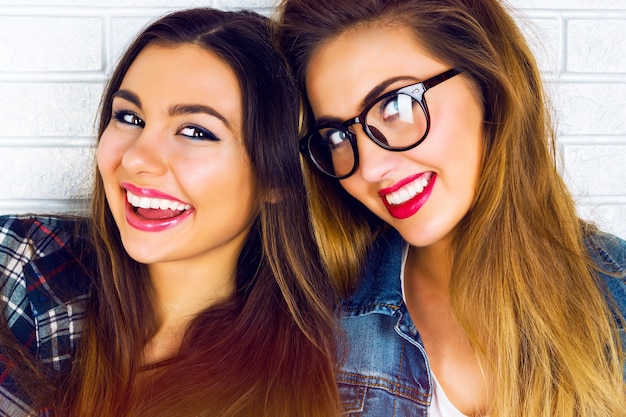 Портрет двух симпатичных подружек-подростков, улыбающихся и позирующих