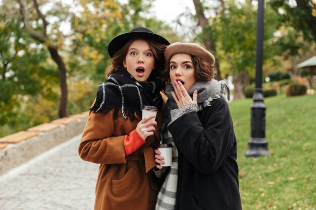 Portrait of two shocked girls dressed in autumn clothes