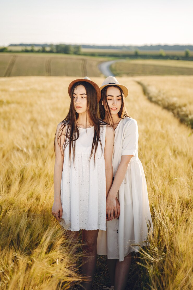 Free Photo portrait of two sisters in white dresses with long hair in a field