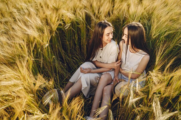 Portrait of two sisters in white dresses with long hair in a field