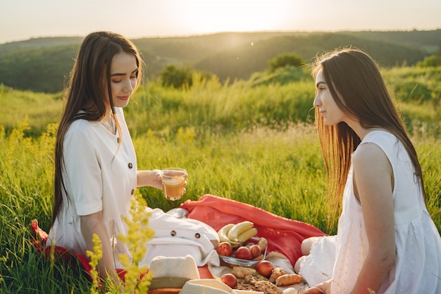 Free photo portrait of two sisters in white dresses with long hair in a field