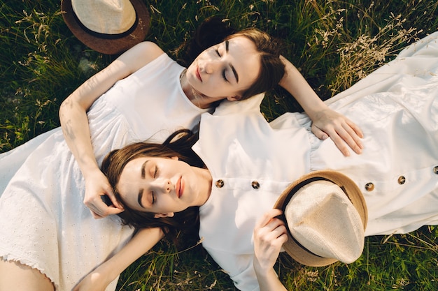 Ritratto di due sorelle in abiti bianchi con i capelli lunghi in un campo