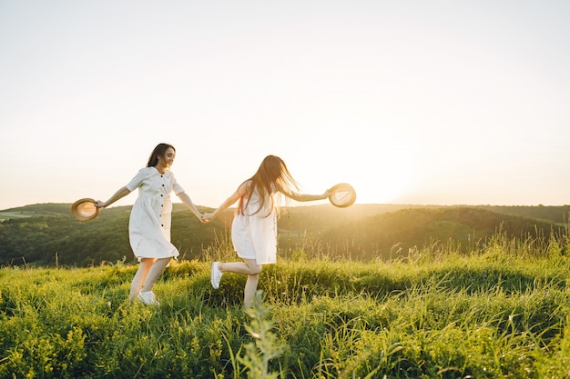 Portrait of two sisters in white dresses with long hair in a field