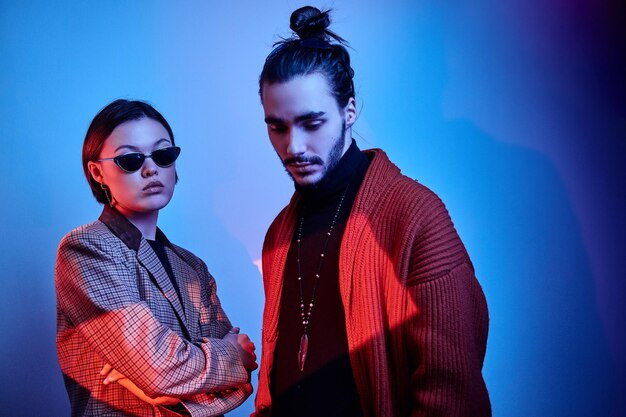 Portrait of two trendy persons in fashionable clothing over blue background.