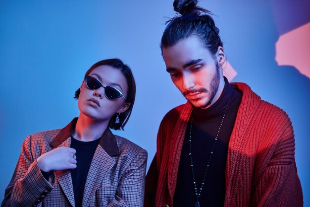 Portrait of two trendy persons in fashionable clothing over blue background.