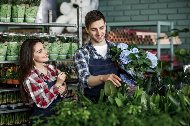 Portrait of two workers in special clothes working in garden center greenhouse