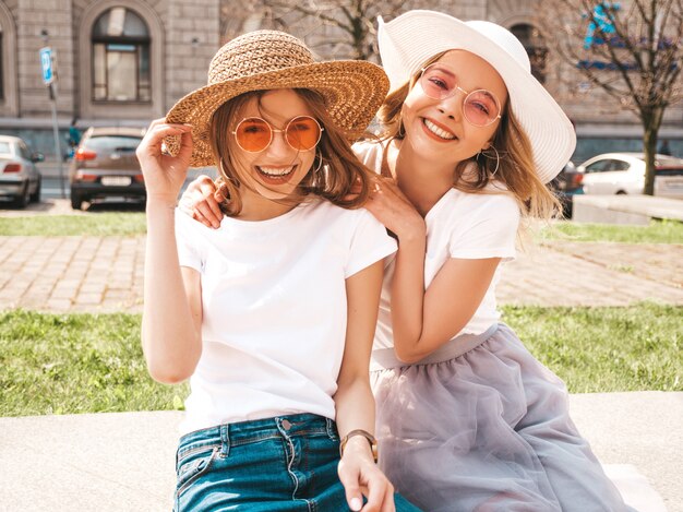 トレンディな夏の白いtシャツ服で流行に敏感な女の子を笑顔2つの若い美しいブロンドの肖像画。