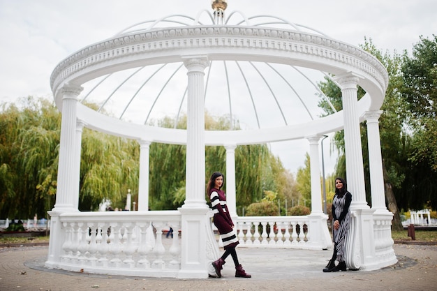 Free photo portrait of two young beautiful indian or south asian teenage girls in dress background white temple arch