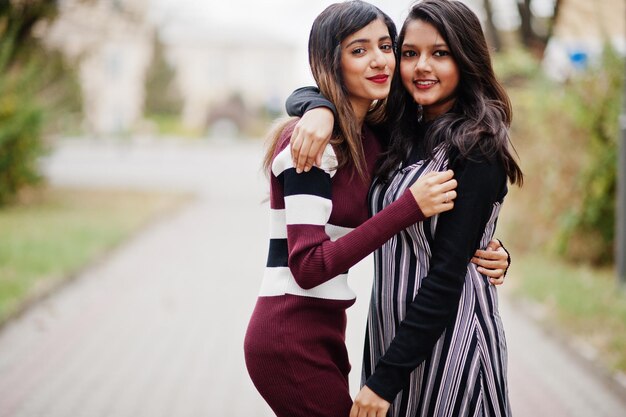 Portrait of two young beautiful indian or south asian teenage girls in dress walking together on street