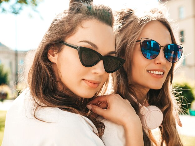 Портрет двух молодых красивых улыбающихся хипстерских женщин в модной летней белой футболке