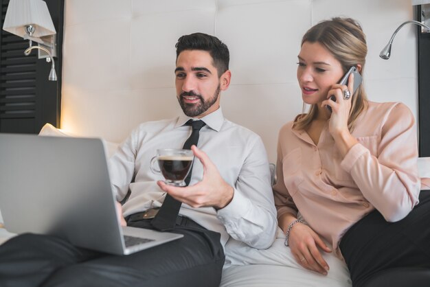 Portrait of two young business people working together on the laptop at the hotel room. Business travel concept.