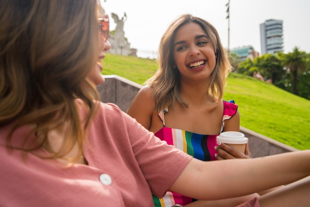 Free photo portrait of two young friends spending good time together and talking while sitting on stairs outdoors. urban concept.