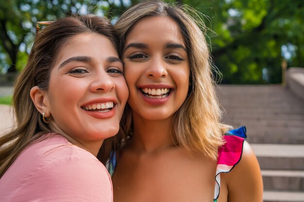 Portrait of two young friends spending good time together while standing outdoors. Urban concept.