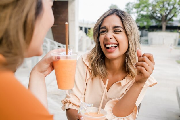 屋外のコーヒーショップで一緒に時間を過ごす2人の若い友人の肖像画。アーバンコンセプト。