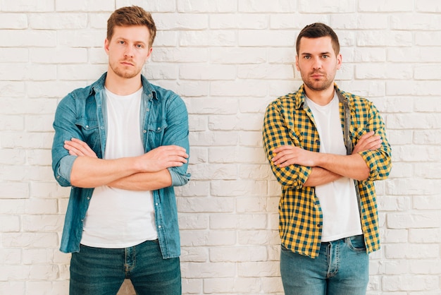 Free photo portrait of two young male friends with their arms crossed looking at camera