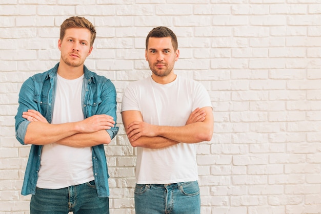 腕を組んで白い壁に立っている2人の若い男性の友人の肖像画