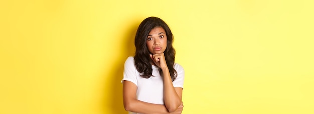 Free photo portrait of unamused and bored africanamerican teenage girl looking reluctant at camera standing ove