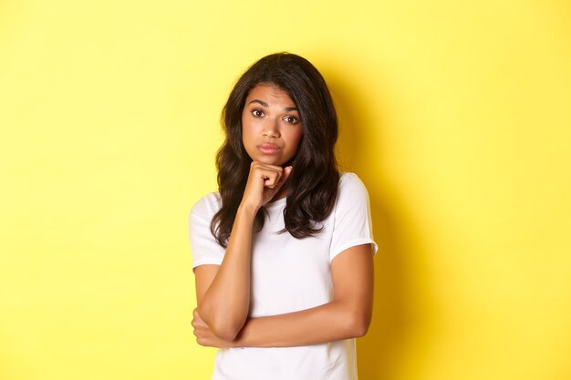 Portrait of unamused and bored africanamerican teenage girl looking reluctant at camera standing ove...