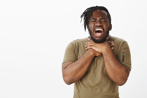 Free photo portrait of unhappy guy in a brown t-shirt posing against the white wall