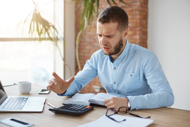 Portrait of unhappy mature bearded accountant working in company office