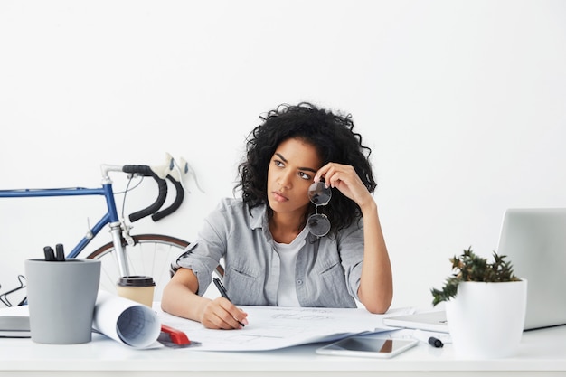 Free photo portrait of unhappy and tired young afro american female architect working on blueprints