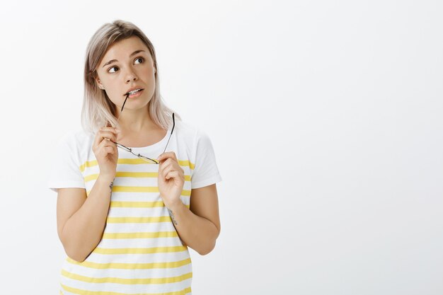 Portrait of unsure blonde girl with glasses posing in the studio