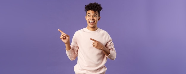 Portrait of upbeat goodlooking hispanic man with dreads smiling amused looking and pointing upper le