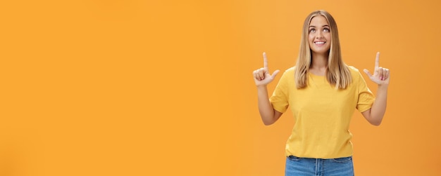 Portrait of upbeat joyful beautiful young caucasian girl with tan and fair hair looking and pointing