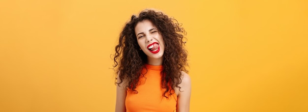 Free photo portrait of upbeat playful and stylish caucasian girl with curly hair and red lipstick winking showi
