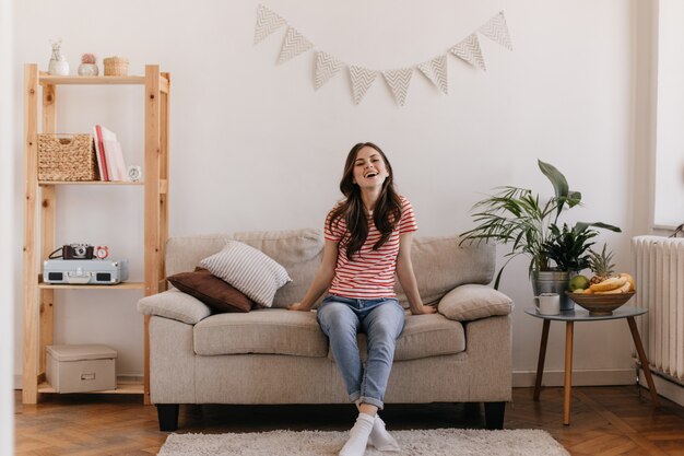 Portrait of upbeat woman dressed in striped top and denim pants