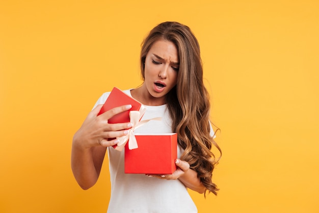 Free photo portrait of an upset disappointed girl opening gift box