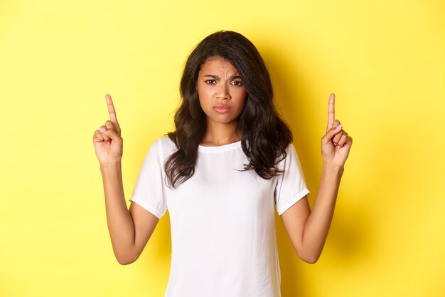 Portrait of upset and disappointed teenage africanamerican girl complaining and frowning pointing