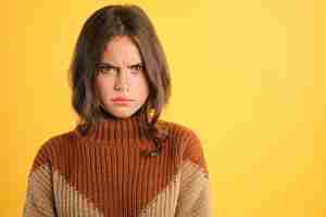 Free photo portrait of upset girl in cozy sweater angrily looking in camera over colorful background