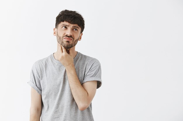 Portrait of upset handsome guy posing against the white wall