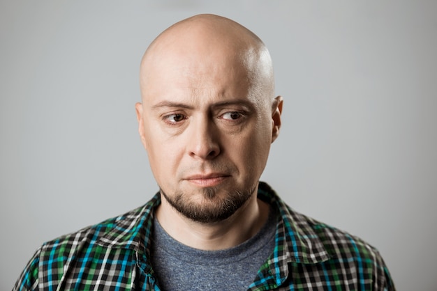 Portrait of upset handsome man thinking over beige wall