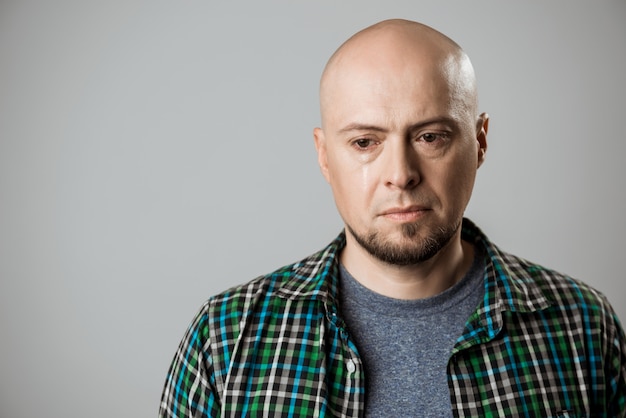 Free photo portrait of upset handsome man thinking over beige wall