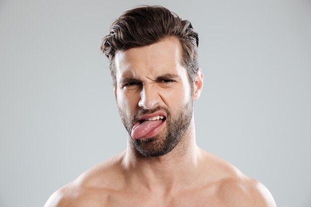 Портрет расстроенного раздраженного голого бородатого мужчины, показывающего язык