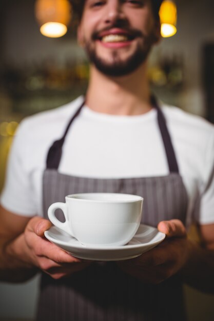 Portrait of waiter holding cup of coffee