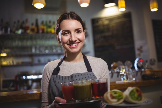 Portrait of waitress holding plate of juices