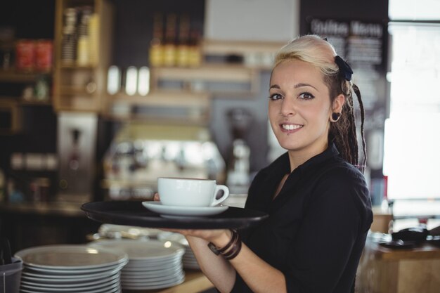 Portrait of waitress standing with cup of coffee