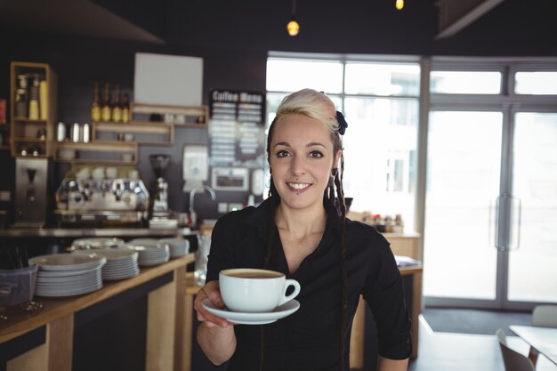 Portrait of waitress standing with cup of coffee